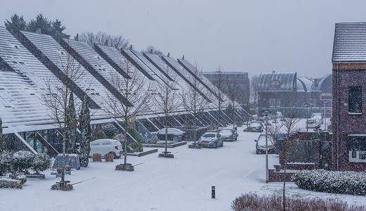 雪天摔跤摄影照片_冬季的荷兰村庄，一个现代荷兰村庄的街道，雪天，荷兰的城市景观