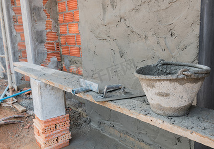 水泥桶摄影照片_红砖墙背景的水泥桶和工具施工