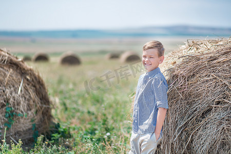 坐在干草堆上微笑的迷人男孩