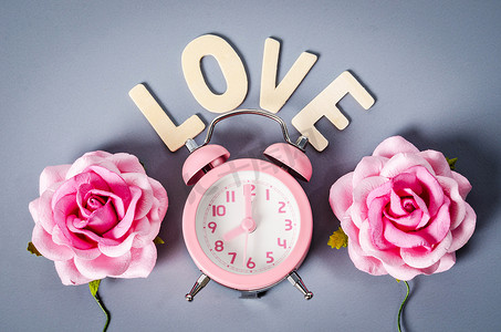 粉红色的闹钟和粉红色的玫瑰与情话。