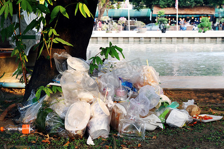 废塑料堆、垃圾塑料、垃圾场、树河背景下堆放塑料袋和湿食物垃圾，污染自然生态