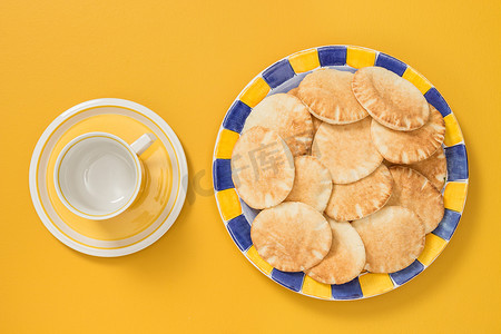 黄色背景中带皮塔面包的茶杯和盘子