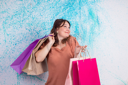购物时笑得开心的女人拿着彩色纸袋，包