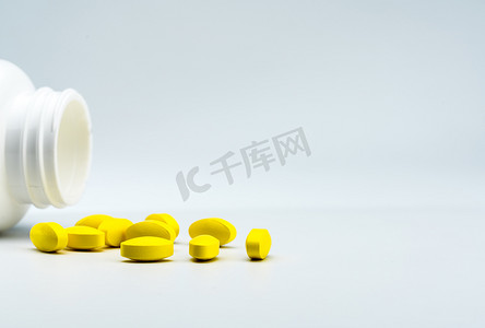 黄色椭圆形药片和白色背景上打开的白色瓶子，带有漂亮的创意图案和文本复制空间。