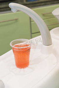 粉色漱口杯摄影照片_牙医手术中的漱口水饮料杯