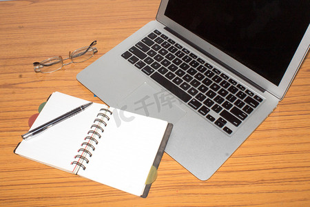 材质好摄影照片_有开放记事本、笔、眼镜的书桌，很好地安置在办公桌上。