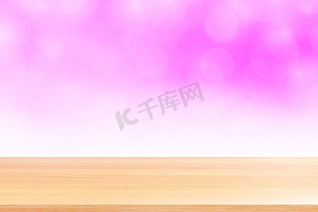 粉红渐变摄影照片_空木桌地板在模糊的散景柔和的粉红色白色渐变背景上，木板空在粉红色散景彩色浅色阴影上，彩色散景灯渐变柔和，用于横幅广告产品