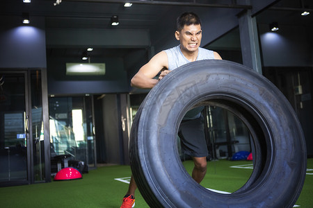 强壮的肌肉男举起轮胎作为他健身计划的一部分。 
