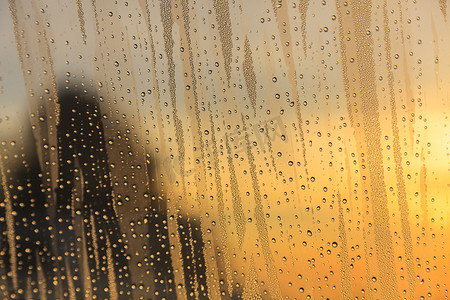 下雨夕阳摄影照片_夕阳下的玻璃上的雨