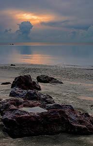 美丽黄昏日出时靠近海边的大红石