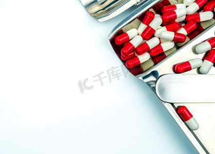不锈钢药物托盘上红色、白色抗生素胶囊药丸的俯视图。