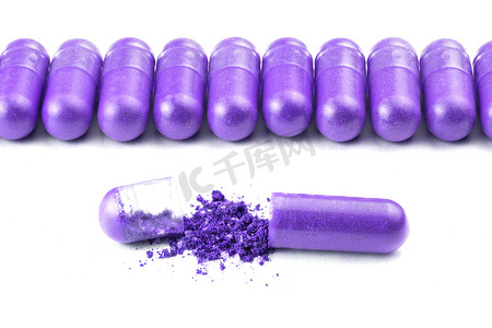 白色背景上分离的一排质子紫色有机胶囊，特写一个打开