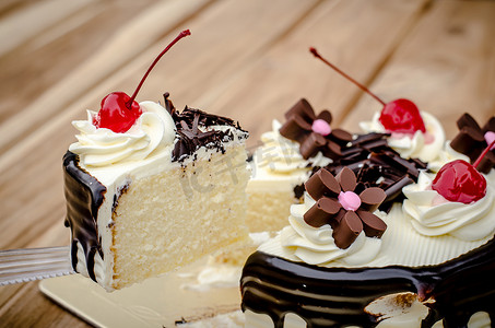 生日蛋糕，香草巧克力樱桃在木桌上被分成几块。