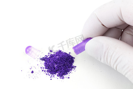 手戴医用手套打开质子紫色有机药物胶囊，白色背景特写