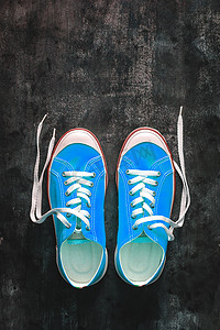 黑暗系摄影照片_深色 c 上未系鞋带的蓝青绿绿松石色运动鞋