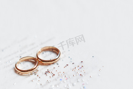 纸质邀请函上的金色结婚戒指，镶有闪亮的水钻。