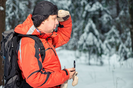 一个背着背包和指南针的人在白雪皑皑的森林里迷路了