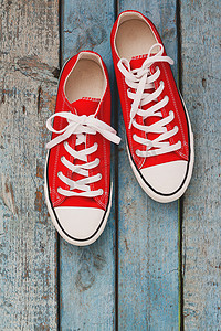 红色复古背景摄影照片_红色复古运动鞋，特写，蓝色木质背景
