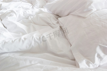 床上白色枕头的顶视图和皱纹凌乱的毯子我