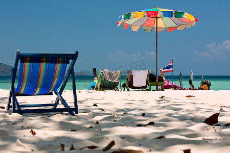 海滩的船摄影照片_泰国珊瑚岛科莫多海滩的沙滩伞和椅子