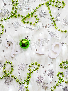 2019新年背景摄影照片_圣诞节和新年背景与数字 2019，银色和绿色装饰品和灯泡。
