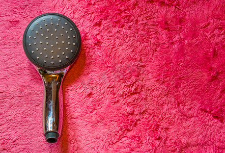 柔和的粉红色地毯背景中隔离的生态友好型现代淋浴头