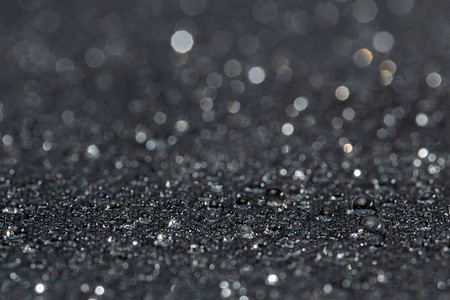 带雨滴的深灰色防水疏水平布，具有选择性聚焦的特写背景