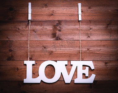 白色爱情文字用绳子和衣夹挂在木制背景上