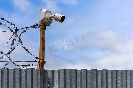 带廉价监控摄像头和带选择性聚焦的铁丝网的异形板栅栏。