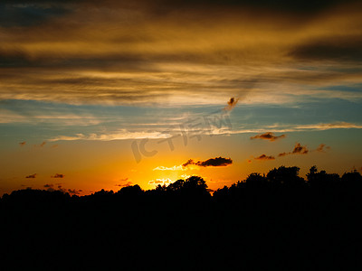 海边夕阳天空摄影照片_夕阳下的树木剪影和海边的云彩
