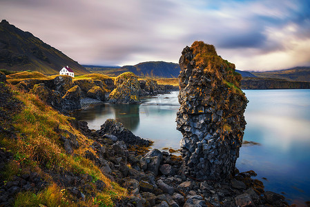 阿尔纳斯塔皮摄影照片_冰岛的海边有悬崖，Arnarstapi 村有一座小房子