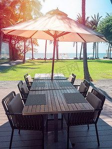 木制餐桌椅摄影照片_带沙滩伞的海景木制餐桌椅