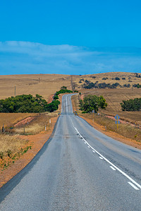 澳大利亚灌木公路穿过干燥的景观和空旷的农田