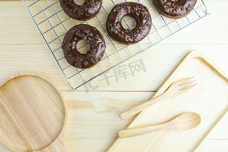 巧克力木板摄影照片_巧克力甜甜圈和木制背景上的木板