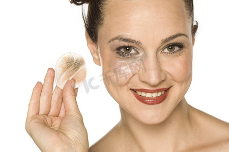 年轻快乐的女人用化妆棉擦脸