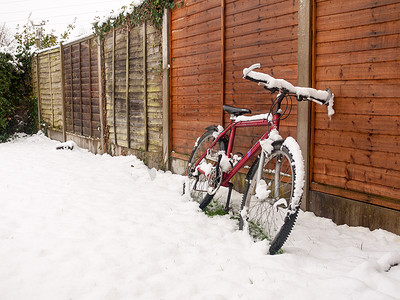 雪地里的红色自行车罩再次休息栅栏雪覆盖地面 w