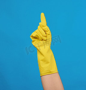 一只手势摄影照片_一只女性手上穿着用于清洁的黄色橡胶手套，蓝色