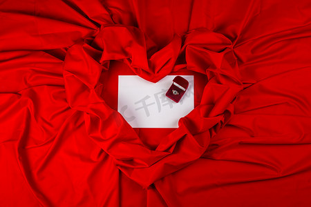 爱情卡摄影照片_红色织物上带钻戒的爱情卡