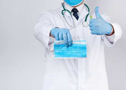 乳汁摄影照片_一件白色外套的医生，蓝色乳汁无菌手套拿着纺织品