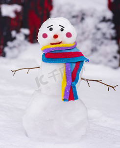 白色小雪人摄影照片_有一条五颜六色的围巾和一张悲伤的脸的滑稽雪人