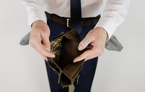 身无分文摄影照片_一个穿西装的男人手里拿着一个空钱包，里面有