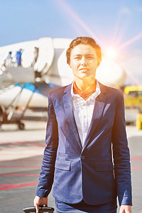 年轻漂亮的空姐站在机场飞机旁的画像