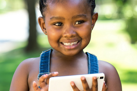 可爱的黑人女孩在智能手机上玩。