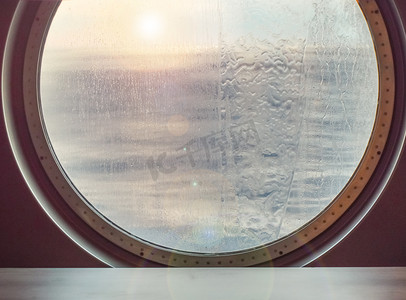 不平静的大海摄影照片_一艘海上游轮的圆形舷窗，外面有水射流。