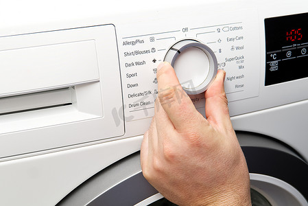 洗衣摄影照片_男人设置程序并打开洗衣机。