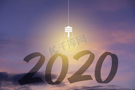 2020 年新年快乐数字与日落天空背景下的灯泡