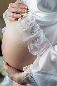 分娩摄影照片_孕妇在家里把手放在肚子上