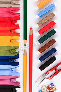 红色剪刀、铅笔和不同颜色的彩色拉链上的纽扣。