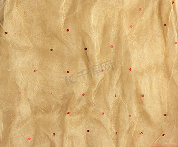 曲线黄色曲线摄影照片_皱巴巴的黄色薄纱，缝有红色圆形亮片，用于 se 的织物