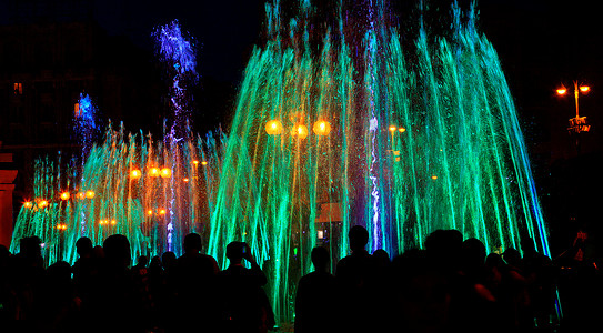 照亮黑暗摄影照片_深夜，五彩缤纷的霓虹灯照亮了强大的城市歌唱喷泉。